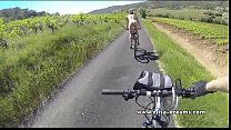 Parpadeando y desnudo en público en bicicleta en la carretera