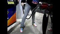 Chica desesperada mojando pantalones vaqueros mientras bombea gasolina
